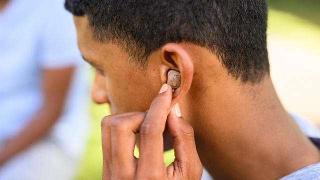 Close up young man putting hearing aid in ear 