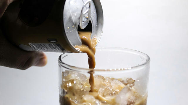 Pouring canned coffee into a glass 
