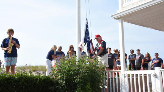 People look on as someone raises a flag in Ocean City 