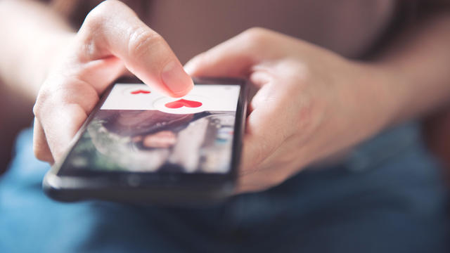 Finger of woman pushing heart icon on screen in mobile smartphone application. Online dating app, valentine's day concept. 