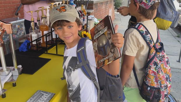 A child holds up a book he received at Squeeze to Please 