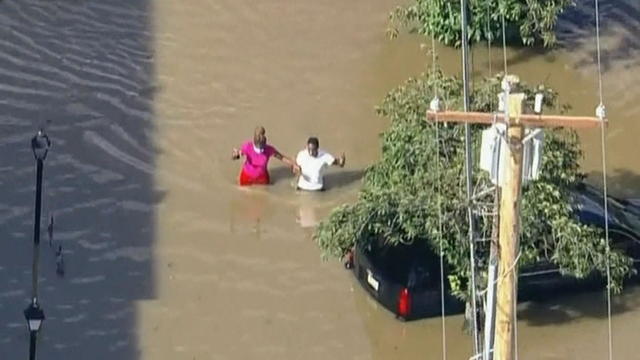 Two people wade through waist-deep water during a flood in Eastwick in Philadelphia 