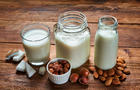 Alternative types of vegan milks in glass bottles on rustic wooden table 