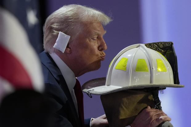 Former President Donald Trump kisses the helmet of Corey Comperatore during the Republican National Convention on Thursday, July 18, 2024, in Milwaukee. 