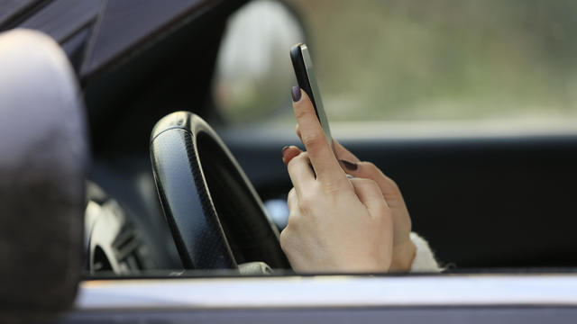Woman driving car distracted by her mobile phone 