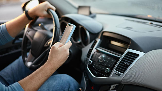 Hands of unrecognizable man driver using mobile phone while driving 