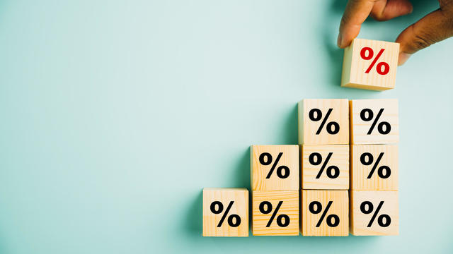 Businessman's hand arranging a wood cube block with a percentage symbol icon 