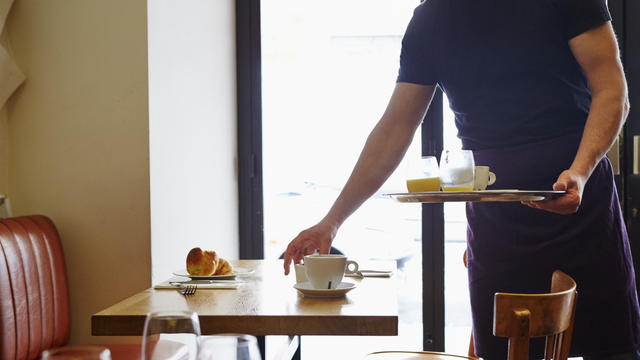 Waiter clearing table in restaurant 