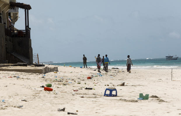 People walk at the scene of an explosion that occurred while revellers were swimming at the Lido beach in Mogadishu 