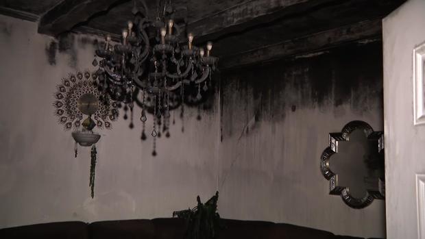 The interior of a fire-damaged home in Queens Village. The ceiling, light fixture and decorations have all been blackened by fire damage. 