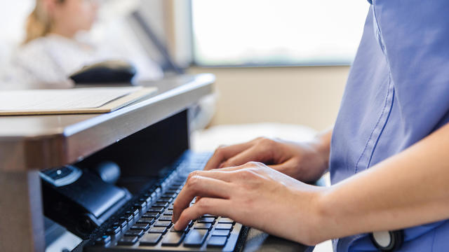 Focus on healthcare worker's hands typing on computer keyboard 