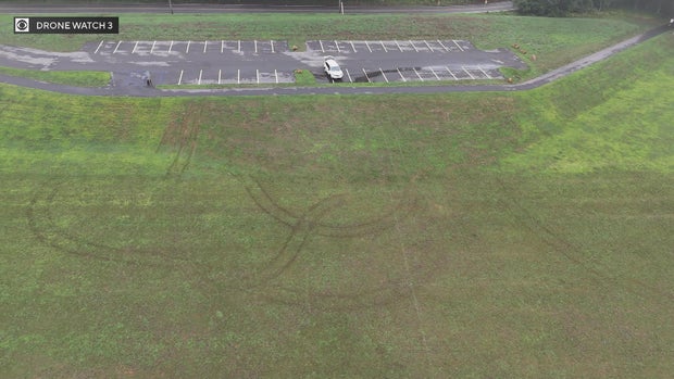 An overhead shot shows deep tire tracks in the rugby field