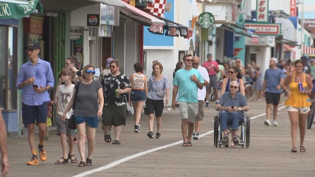 People walk on the Ocean City boardwalk on a sunny day 