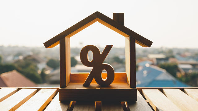 Percentage and house sign symbol icon wooden on wood table. Concepts of home interest, real estate, investing in inflation. 