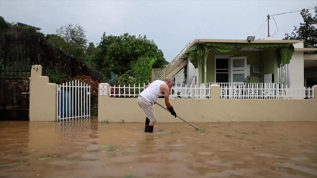 A man in calf-deep water works outside after Hurricane Ernesto hit Puerto Rico 