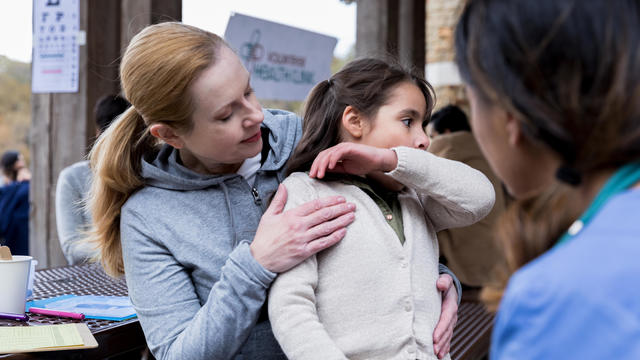 mother holds sick, coughing child at health clinic 