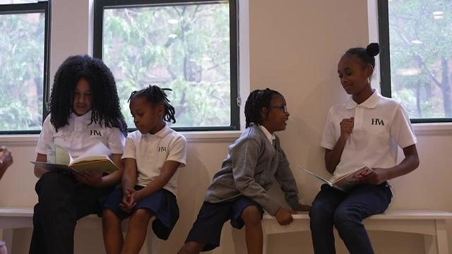 Four students sit on benches and read together. 