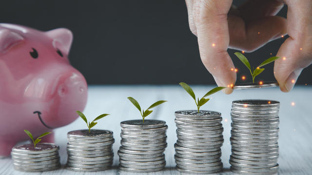 Close up of male hand stacking coins and Trees growing on coin in dark background ,Business Finance and Money, plant growing up on coins and investment budget, saving money investment.concept 