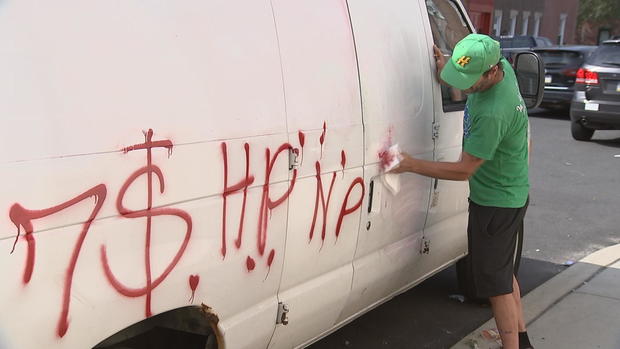 Resident cleans off van that was vandalized with spray paint 