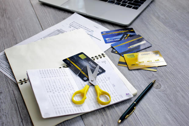 Credit card cut with scissors placed on a table with laptops and bills 