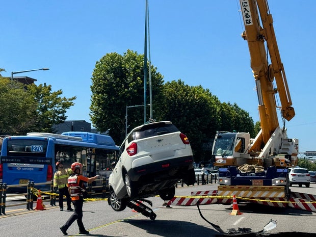 Workers remove an SUV from a sinkhole that opened on a road in central Seoul, South Korea, Aug. 29, 2024, in an image provided by South Korea's National Fire Agency