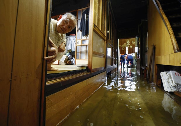 Um homem olha de dentro de sua casa inundada para uma área afetada pelas fortes chuvas causadas pelo tufão Shanshan em Ogaki.