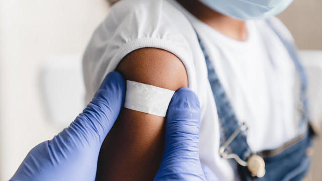 Covid 19 measles, ebola vaccinated. Doctor pediatrician injecting making vaccine to little african girl in medical clinic. Nurse applying medical patch after injection 