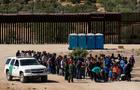 Migrants wait to be processed by U.S. Border Patrol agents after crossing into the U.S. from Mexico on June 14, 2024, in Jacumba Hot Springs, California. 