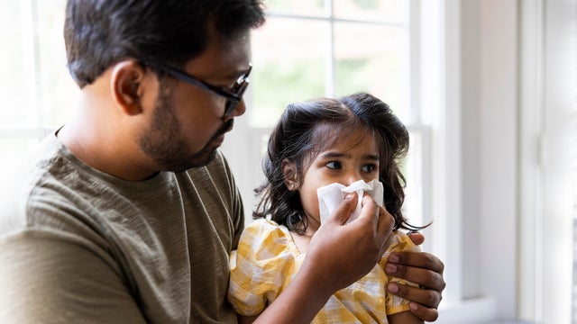 Father wiping toddler daughters nose 