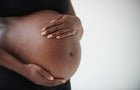 Midsection of pregnant Black woman holding belly 