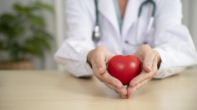 Unrecognizable doctor holding red heart shape in hands. 