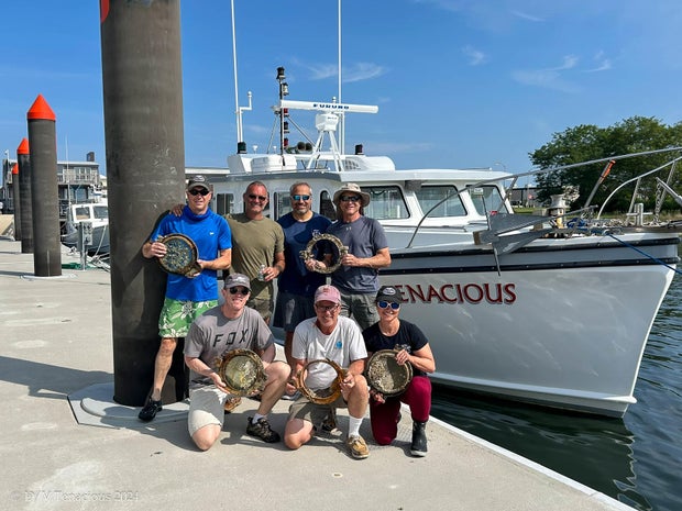 Discovery team members hold portholes recovered from the wreck. D/V Tenacious