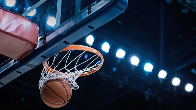 Basketball scoring a basket as it goes through the hoop 