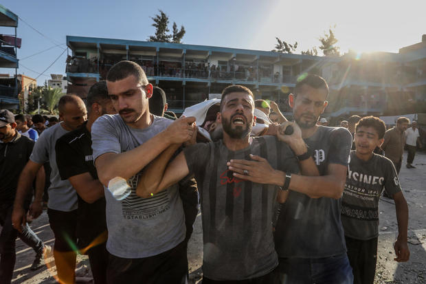 People carry the body of Yaser Abu Sharar, a staff member of the United Nations Relief and Works Agency for Palestine Refugees in the Near East (UNRWA) who was killed in an attack by the Israeli army on a UNRWA-run school being used as a shelter for displaced people in Nuseirat, in central Gaza