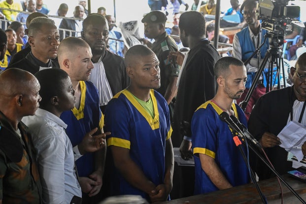 From left, Tyler Thompson Jr., Marcel Malanga and Benjamin Reuben Zalman-Polun, all American citizens, face the court in Kinshasa with 52 other defendants on June 7, 2024, accused of playing a role in an attempted coup in Congo.