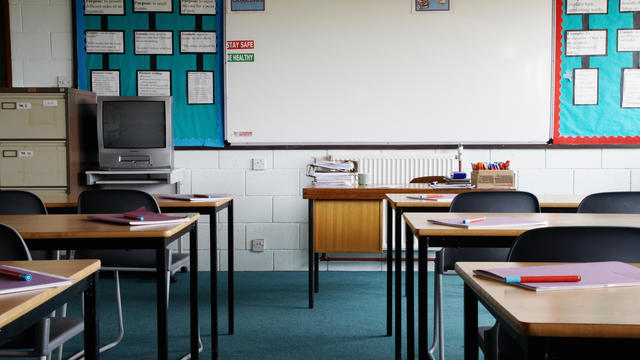 Empty school classroom, exercise books and pens on table 