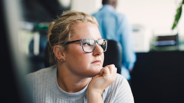 Female entrepreneur with hand on chin looking away in office