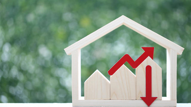 Model house and red arrow graph on natural green background,Business investment and real estate concept 