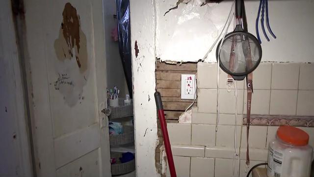 The inside of a Passaic apartment. A wall is cracked and falling apart and paint has peeled off a door. 