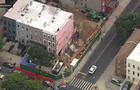 An aerial view of a construction site alongside a row of Brooklyn homes. 