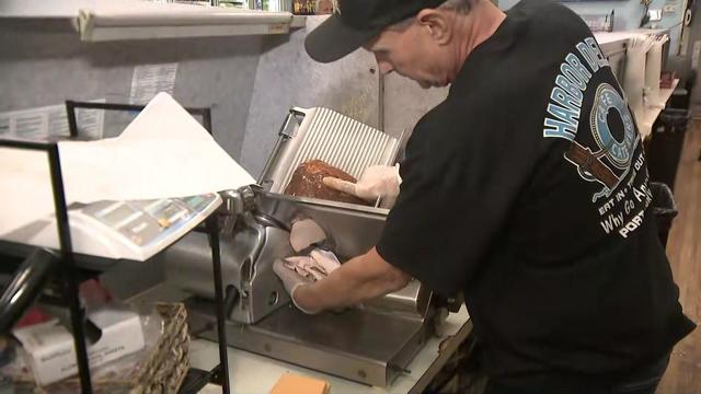 A deli employee slices meat. 