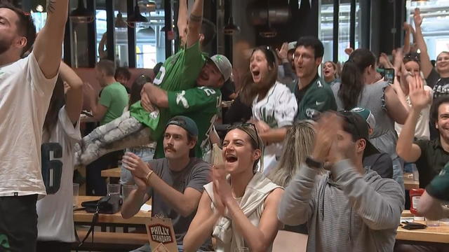 Fans wearing Eagles gear cheer and celebrate while watching the game at Yards Brewing 