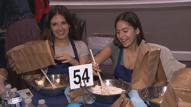 Two girls smile while making challah 