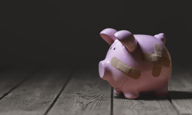 Broken piggy bank with band aid bandage or plaster finance background 