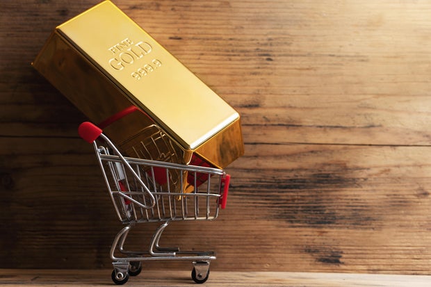 Large shiny gold bar put in a tiny shopping cart.