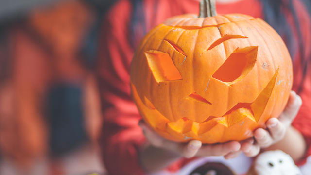 Boy holding a jack-o-lantern pumpkin decoration 