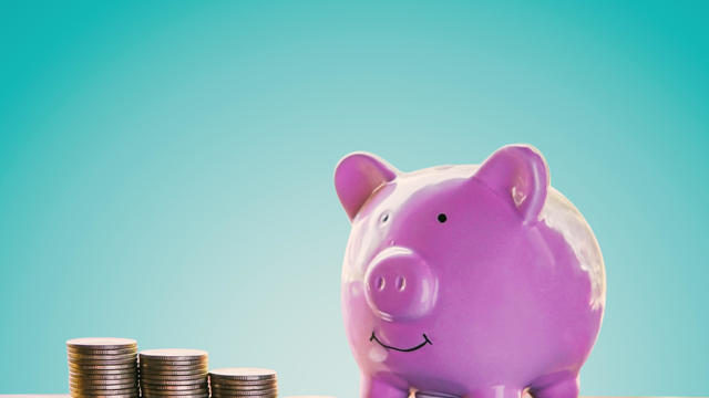 Piggy bank and coins on wood plank with blue background, saving and growing concept. 