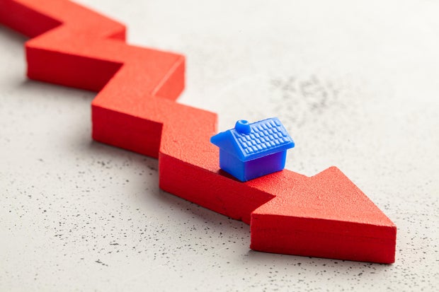 House and red arrow down. Falling real estate prices. Reduced insurance or tax rate