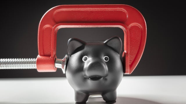 Piggy bank squeezed with red clamp financial problems