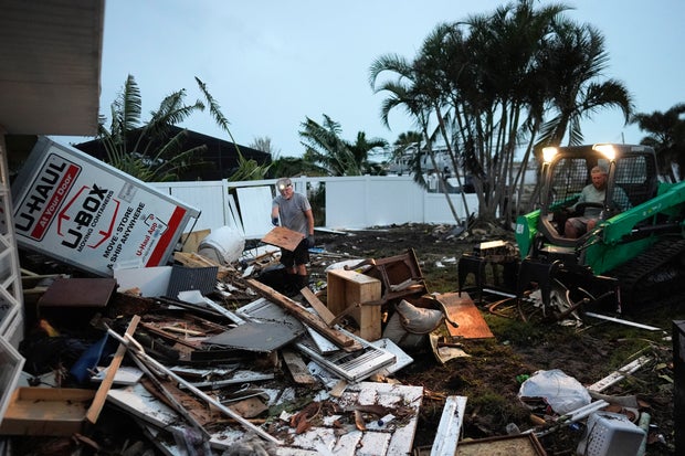 Homeowner Robert Turick, 68, left, and storm waste removal contractor Sven Barnes work to clear debris that storm surge from Hurricane Milton swept from other properties into Turick's canal-facing backyard, in Englewood, Florida, Oct. 11, 2024.